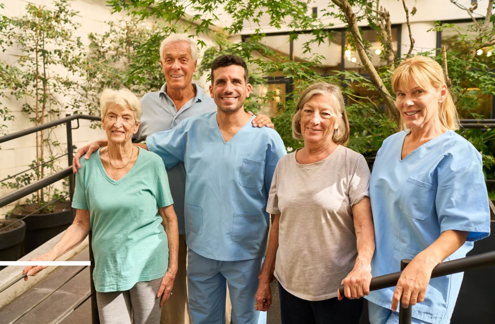 Seniors and caregivers enjoy outdoor time together, demonstrating companionship, compassionate care, and strong partnerships in the industry.